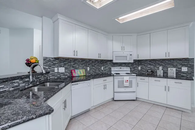 a kitchen with granite countertop a sink a stove and cabinets