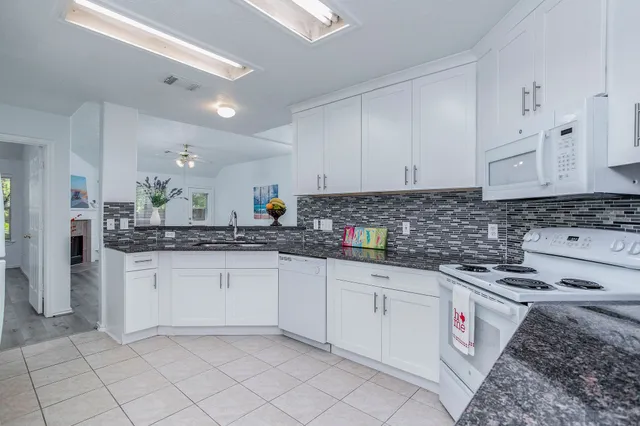 a kitchen with granite countertop a sink a stove and cabinets