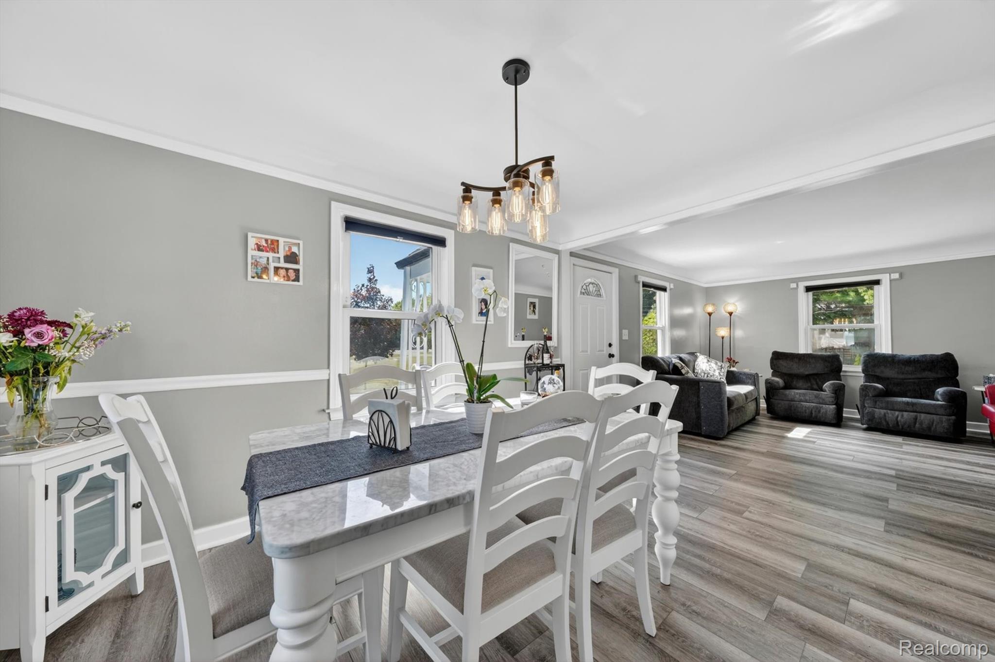 2861 John R Road Rochester, MI 48307 - Photo 17 of 54 Dining area featuring a modern chandelier, wood-finish flooring, two-tone painted walls with chair rail molding, and white trim