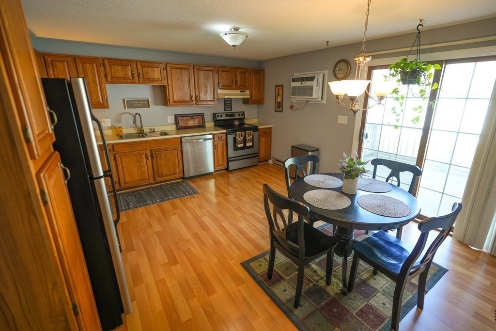 283 Fuller Road, Unit E Chicopee, MA 01020 - Photo 6 of 21 a kitchen with a table chairs refrigerator and microwave