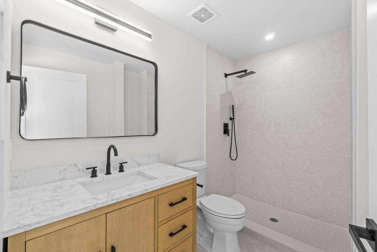 4498 Northwest 2nd Avenue Boca Raton, FL 33431 - Photo 12 of 43 a bathroom with a granite countertop sink a toilet and a mirror