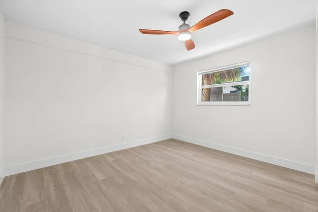 an empty room with a window and a ceiling fan