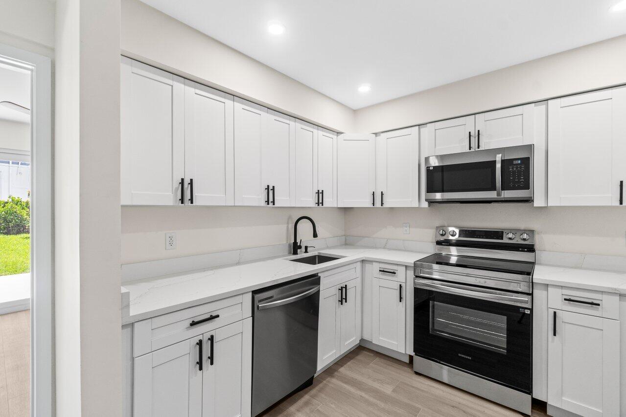 4498 Northwest 2nd Avenue Boca Raton, FL 33431 - Photo 28 of 43 a kitchen with granite countertop a sink stainless steel appliances and white cabinets