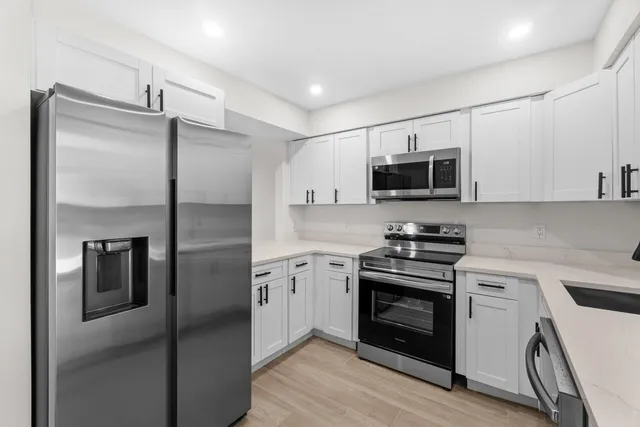a kitchen with cabinets stainless steel appliances and wooden floor