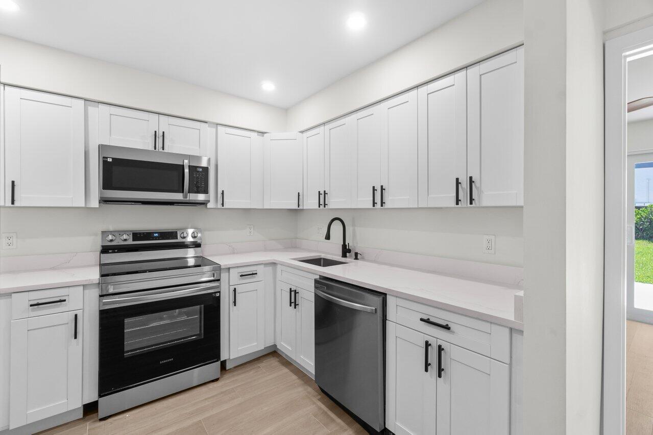 4498 Northwest 2nd Avenue Boca Raton, FL 33431 - Photo 4 of 43 a kitchen with white cabinets and stainless steel appliances