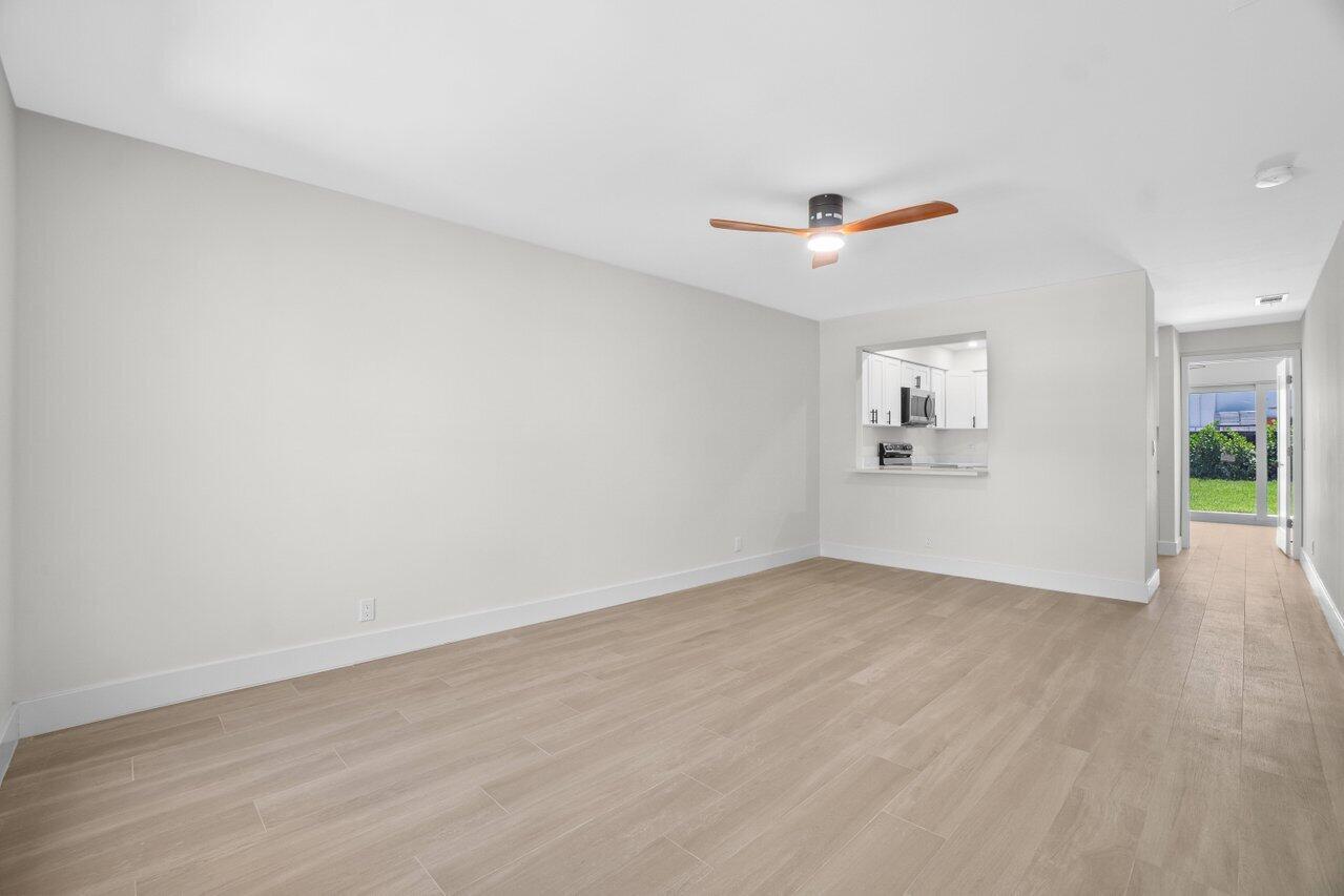 4498 Northwest 2nd Avenue Boca Raton, FL 33431 - Photo 7 of 43 an empty room with wooden floor chandelier fan and windows