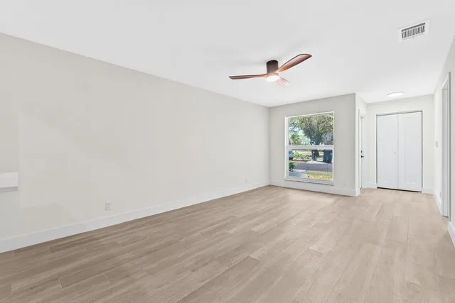 an empty room with wooden floor and ceiling fan