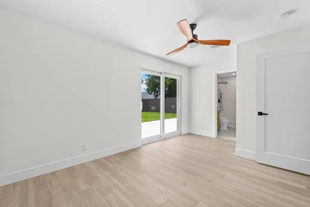 a view of an empty room with wooden floor and a ceiling fan