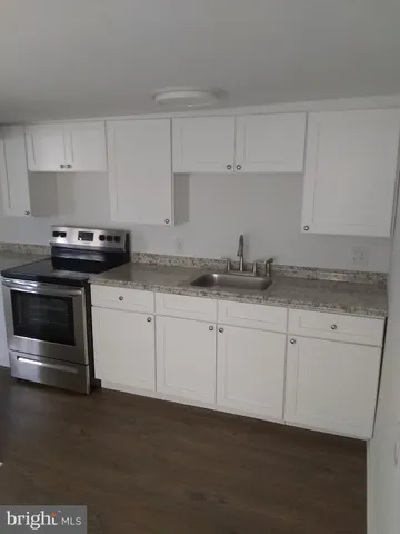 a kitchen with granite countertop white cabinets and stainless steel appliances