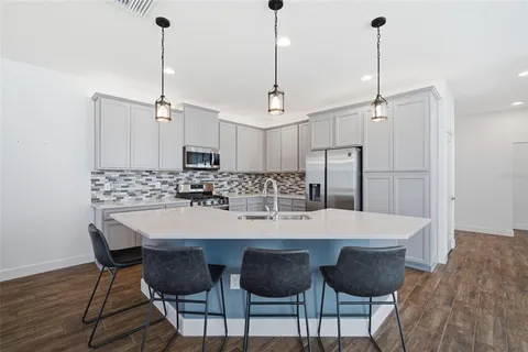 a kitchen with stainless steel appliances kitchen island granite countertop a sink chairs and cabinets
