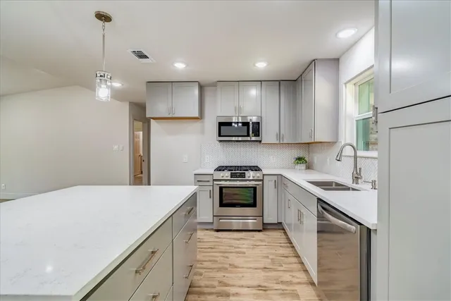 a kitchen with kitchen island a sink stainless steel appliances and cabinets