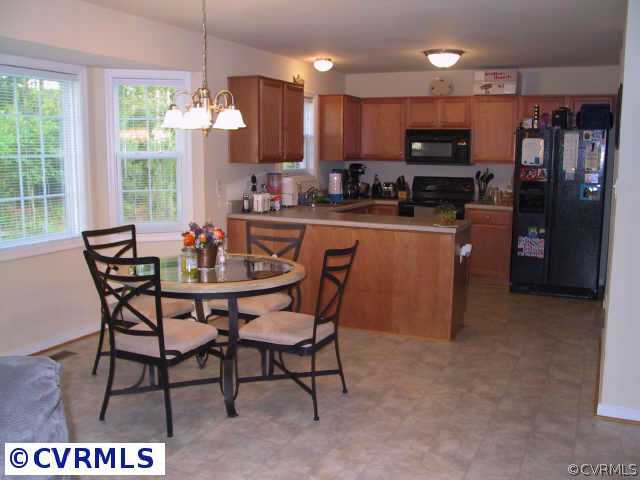 9513 Dunroming Road Chesterfield, VA 23832 - Photo 4 of 6 a kitchen with stainless steel appliances kitchen island granite countertop a dining table chairs and a refrigerator