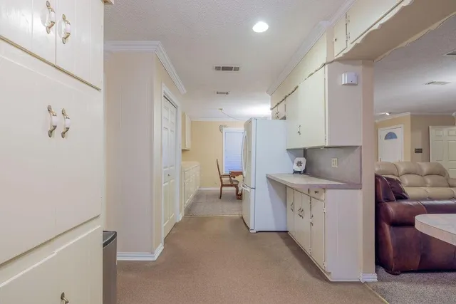 a large white kitchen with cabinets a sink and a refrigerator