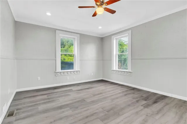 a view of an empty room with wooden floor and a window