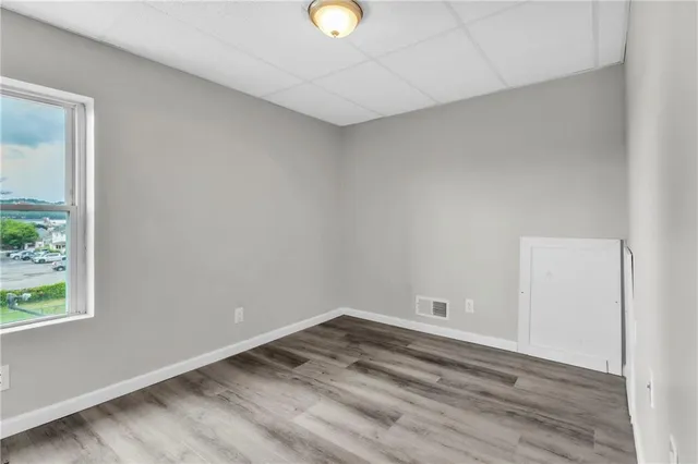 a view of empty room with wooden floor and window