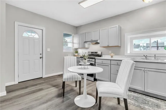 a kitchen with stainless steel appliances granite countertop a white table and chairs in it