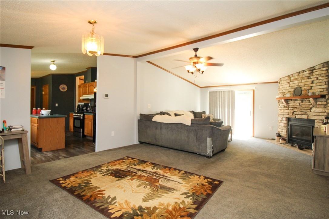 1798 Campbell Road Southwest New Philadelphia, OH 44663 - Photo 14 of 50 Carpeted living room with ceiling fan, a stone fireplace, and lofted ceiling