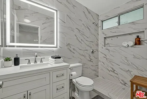 a bathroom with a granite countertop toilet sink and mirror