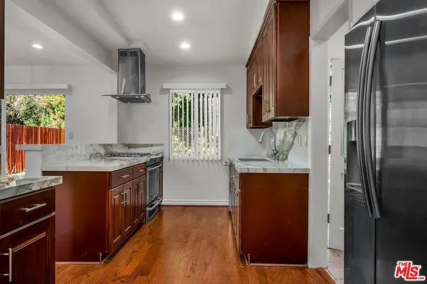 a kitchen with stainless steel appliances granite countertop a refrigerator a sink and a stove