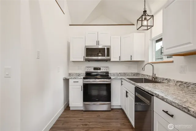 a kitchen with stainless steel appliances granite countertop a stove a sink and a microwave