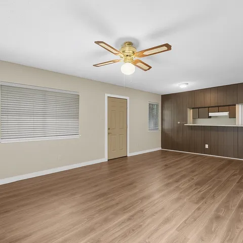 a view of empty room with wooden floor and fan