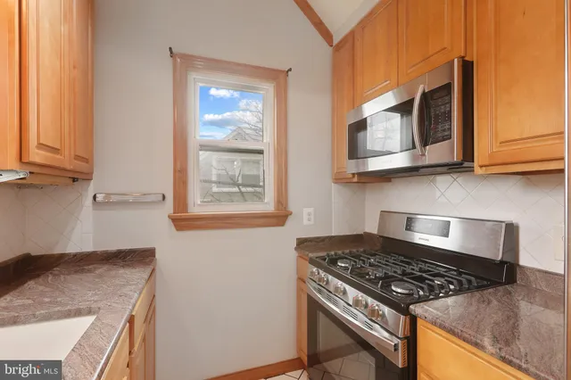 a kitchen with stainless steel appliances granite countertop white cabinets and a stove top oven