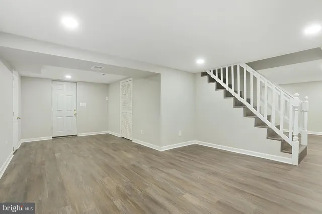 a view of an empty room with wooden floor and stairs