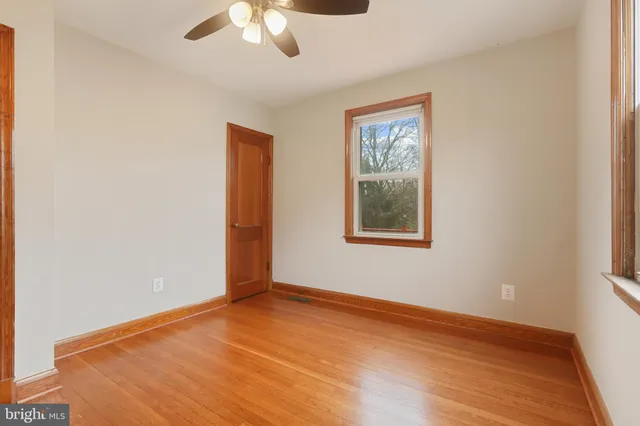 an empty room with wooden floor chandelier fan and windows