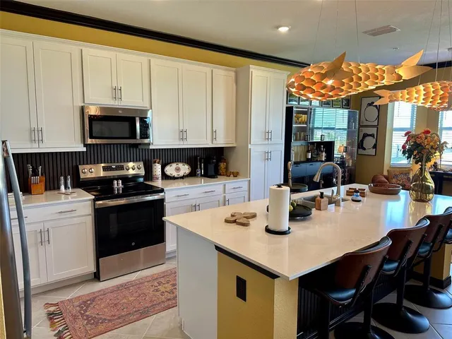 a kitchen with stainless steel appliances granite countertop a table chairs and a stove