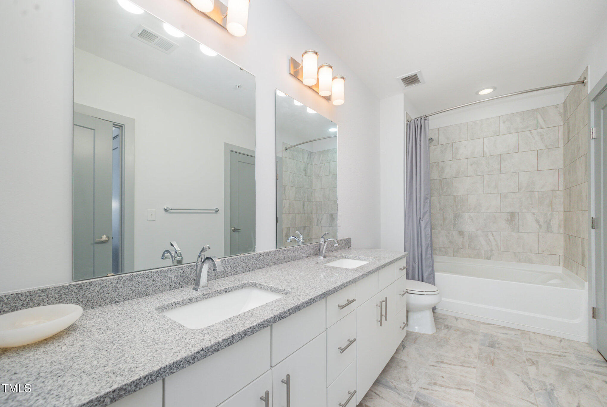 1300 St Marys Street, Unit 408 Raleigh, NC 27605 - Photo 15 of 28 a bathroom with a granite countertop double vanity sink a mirror and a bathtub