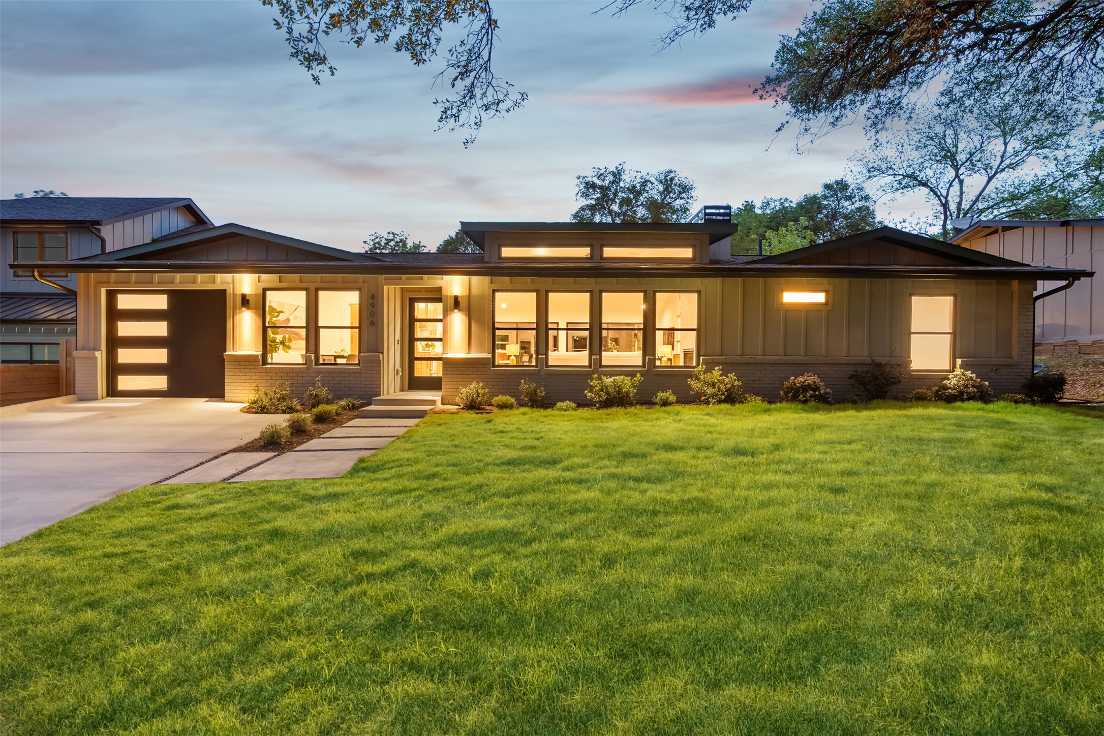 View of front of house featuring a lawn, driveway, and brick siding