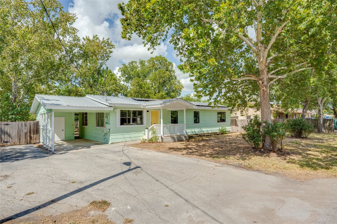 Single story home featuring driveway, a carport, solar panels, and a metal roof