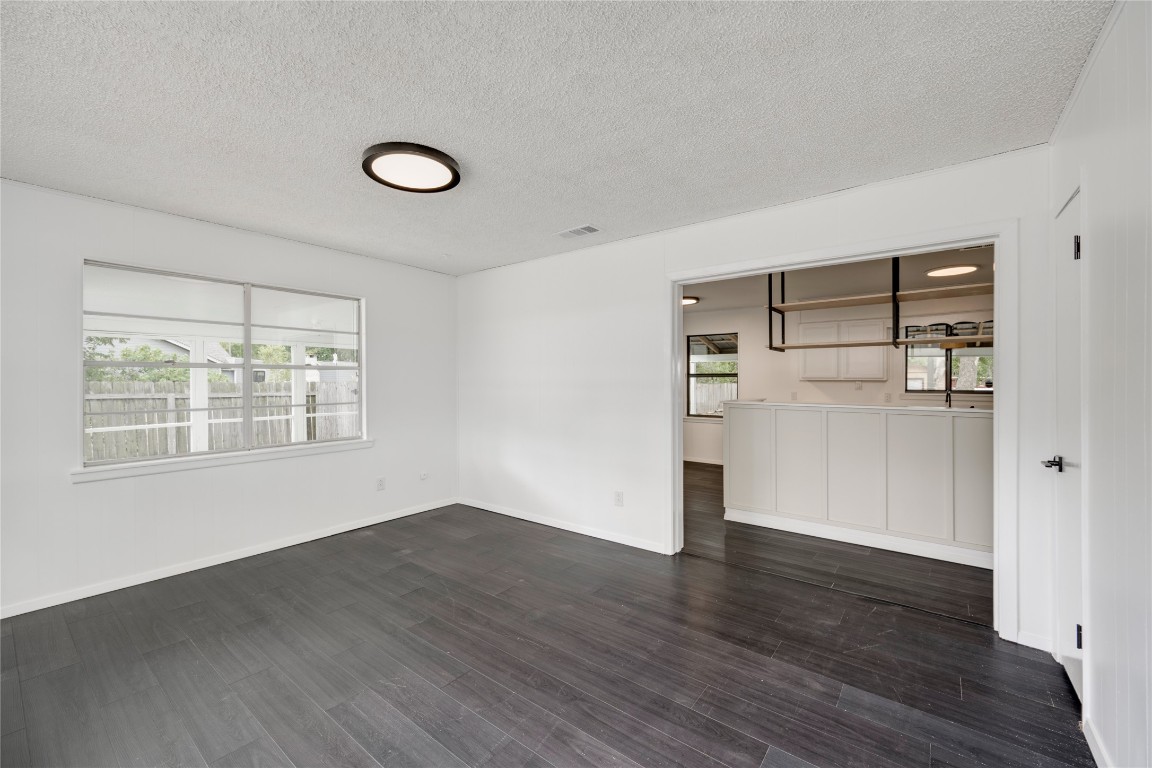 4948 Crossover Road San Marcos, TX 78666 - Photo 4 of 16 Unfurnished living room featuring a textured ceiling and dark wood-style flooring