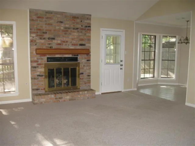 an empty room with a fireplace and large window