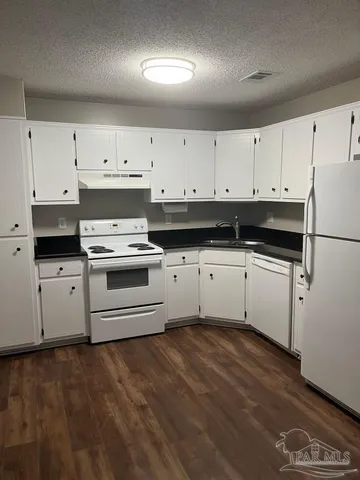 a kitchen with granite countertop white cabinets and white appliances