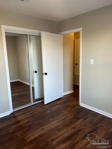 a view of an empty room with wooden floor and closet