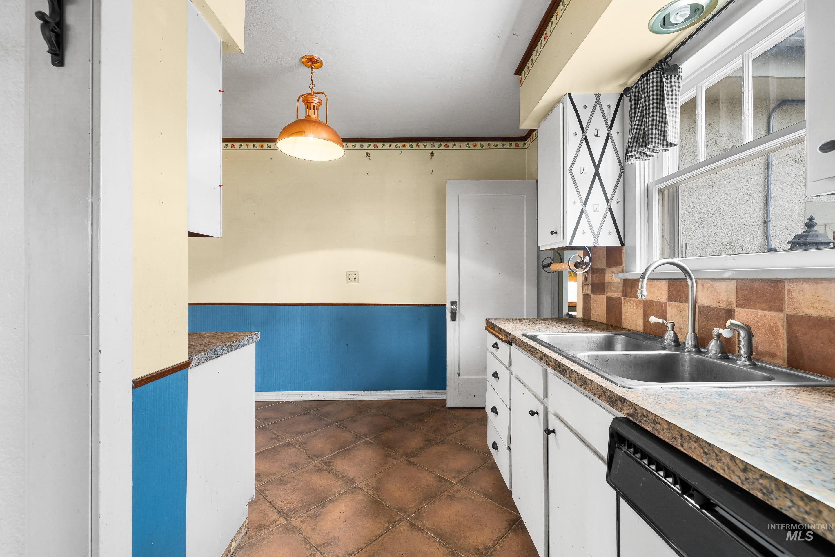 2305 South Gekeler Lane Boise, ID 83706 - Photo 12 of 33 Kitchen with white cabinets, dishwashing machine, hanging light fixtures, and tasteful backsplash