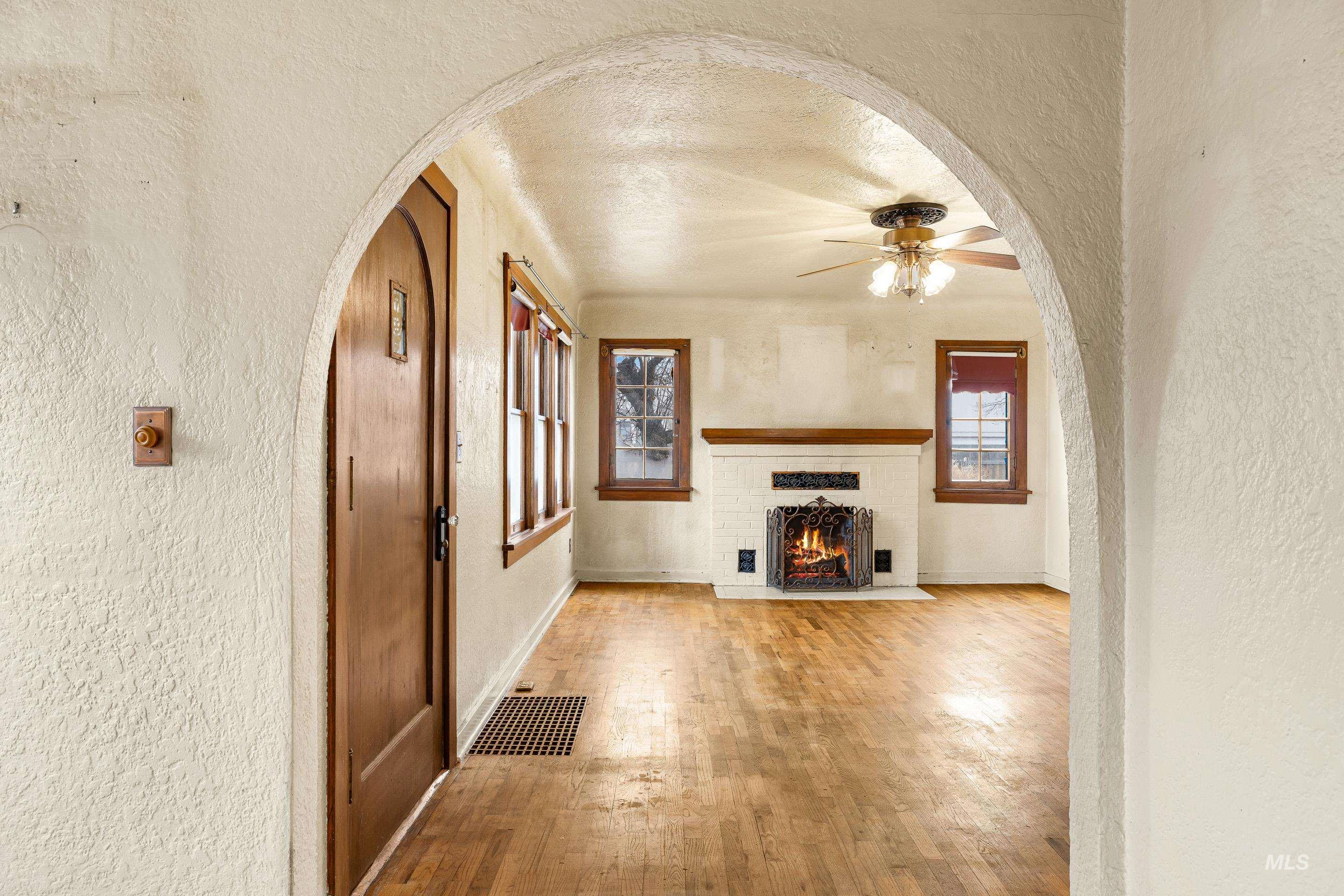 2305 South Gekeler Lane Boise, ID 83706 - Photo 15 of 33 Unfurnished living room featuring arched walkways, a textured wall, plenty of natural light, ceiling fan, and light wood-style flooring