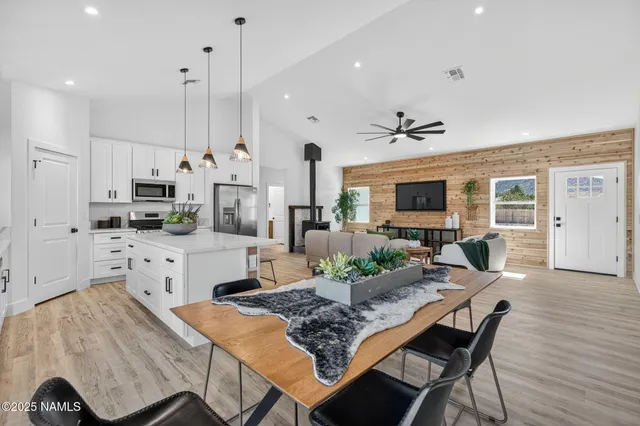 a kitchen with stainless steel appliances kitchen island granite countertop a dining table chairs and white cabinets