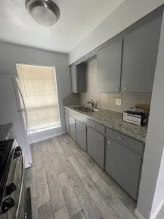 a kitchen with granite countertop a sink a stove and cabinets