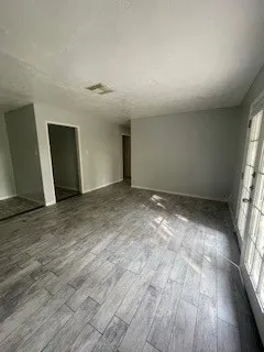 an empty room with wooden floor and windows
