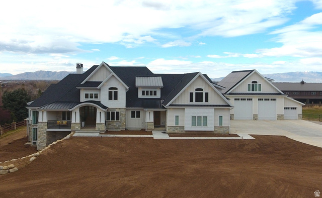 View of front of home with stone siding, a garage, concrete driveway, board and batten siding, and a chimney