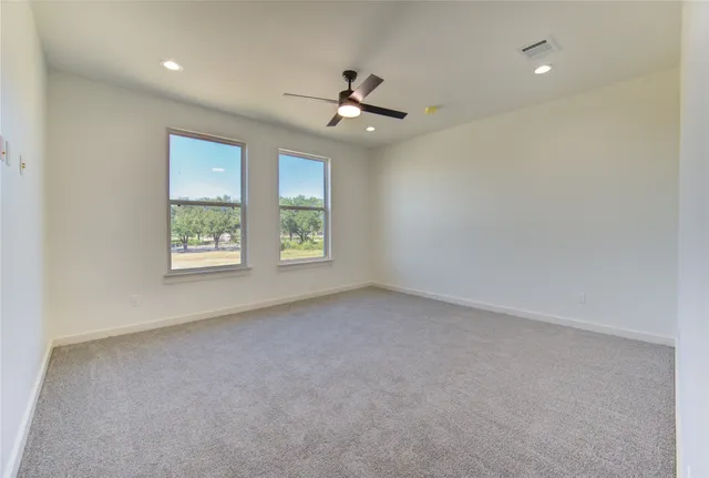 an empty room with windows and ceiling fan