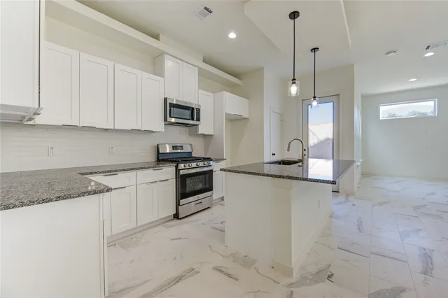 a kitchen with stainless steel appliances granite countertop white cabinets and a stove top oven