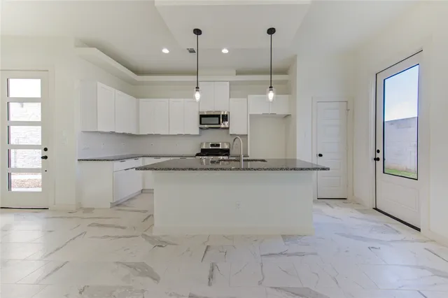 a kitchen with stainless steel appliances granite countertop a sink a stove and a refrigerator