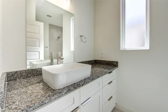 a bathroom with a granite countertop sink and a mirror