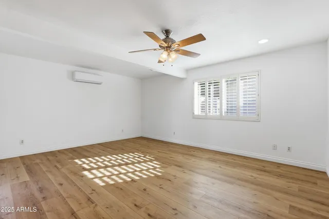 a view of an empty room with window and wooden floor