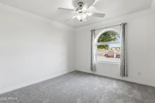 an empty room with a window and a fan