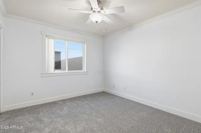 an empty room with a window and ceiling fan