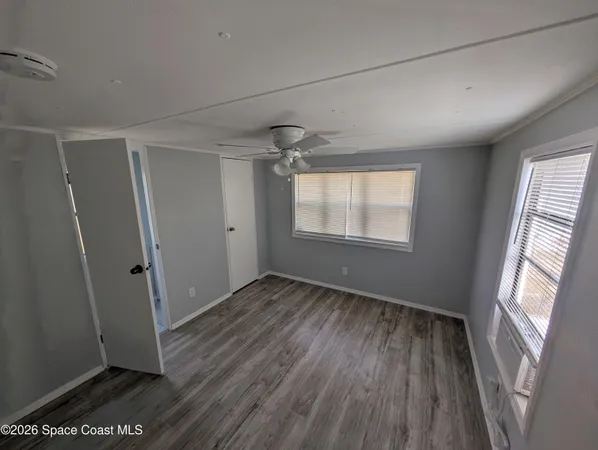 an empty room with wooden floor and windows